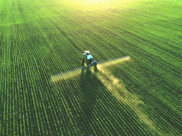 Tractor spraying fertilizer on farm harvest.